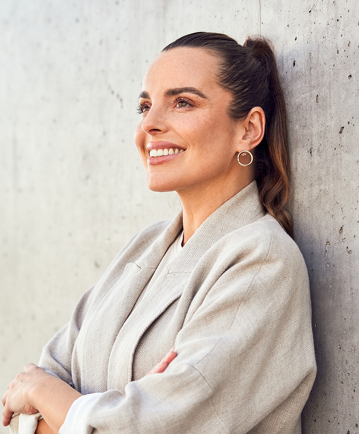 Smiling woman in relaxed pose against wall.