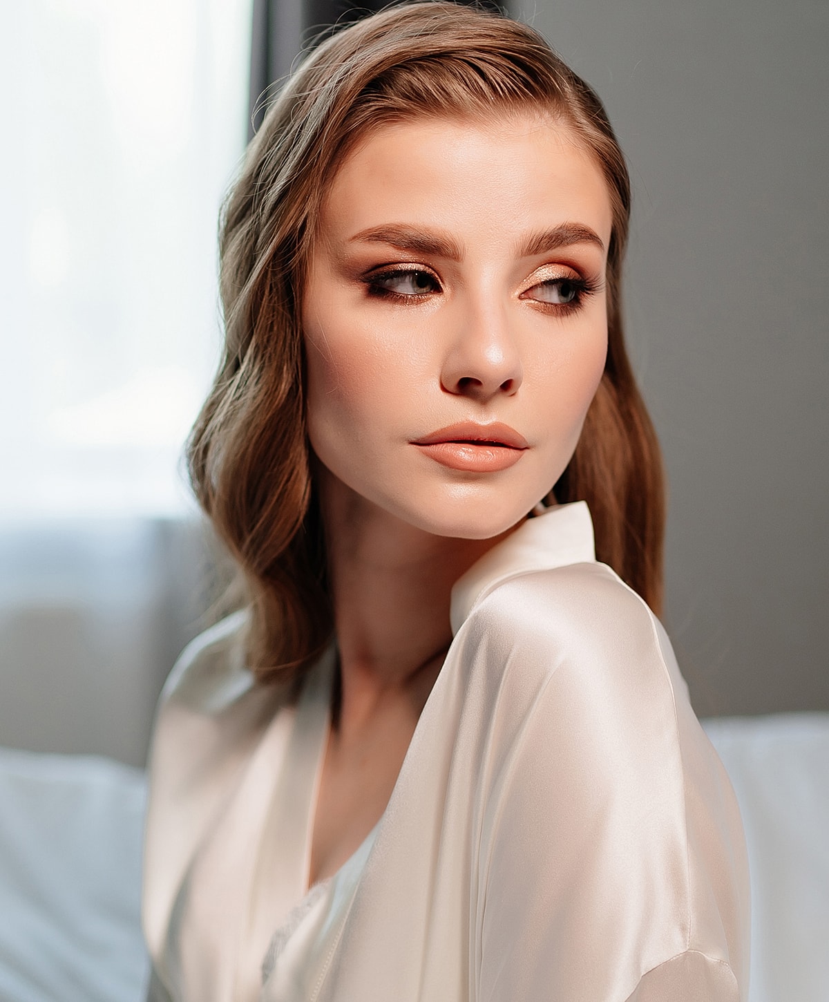 Woman in silk robe with soft, natural makeup.