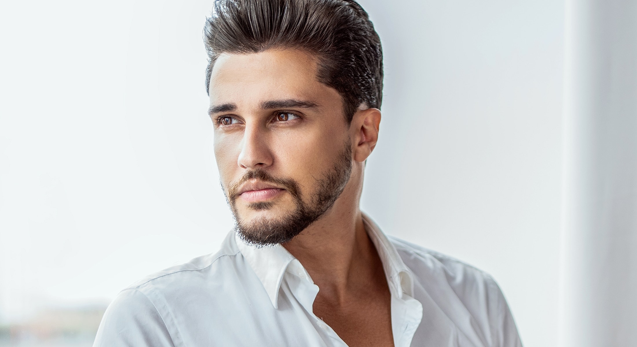 Man with stylish haircut and white shirt.